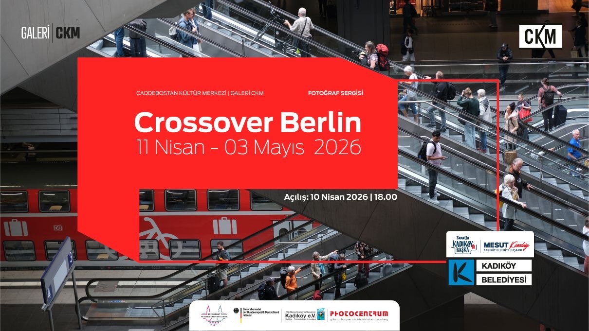 Ein großes rotes Banner kündigt die Fotoausstellung "Crossover Berlin" vom 11. April bis 3. Mai 2026 an. Im Hintergrund sind Menschen auf Rolltreppen in einem modernen Gebäude zu sehen. (KI generierte Beschreibung)
